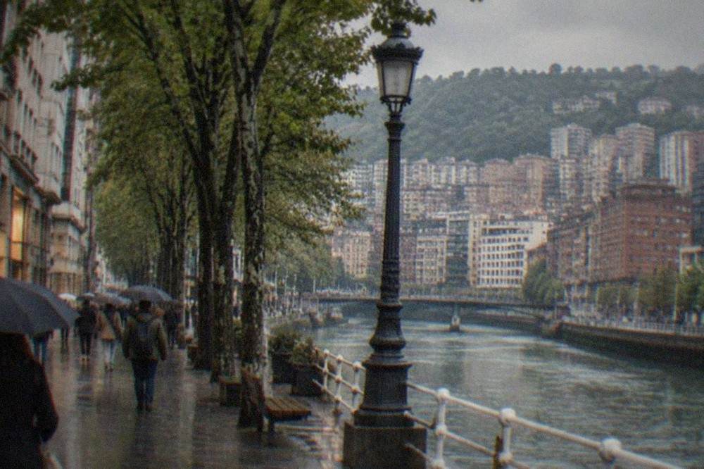A wide tree-lined avenue with department store facades and shoppers in central Bilbao