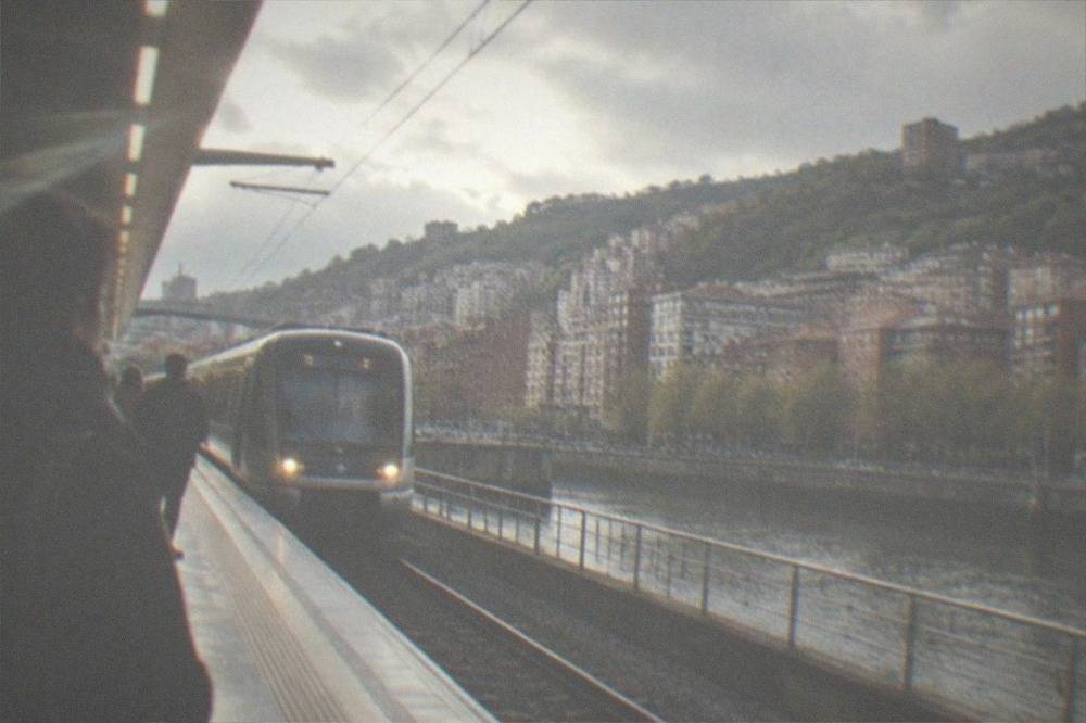 A Metro Bilbao station platform with a train arriving and passengers waiting