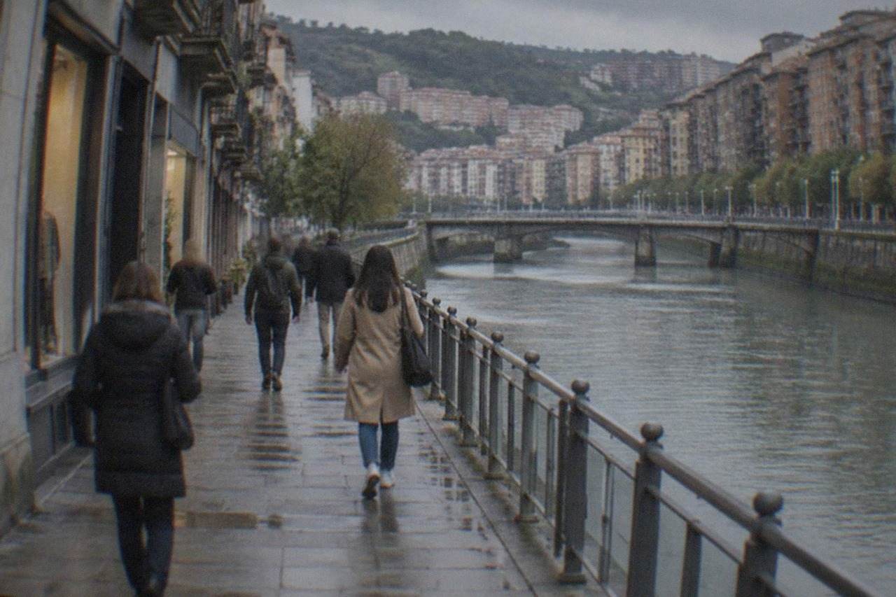 Shoppers walking past small storefronts on a narrow Bilbao street in the afternoon