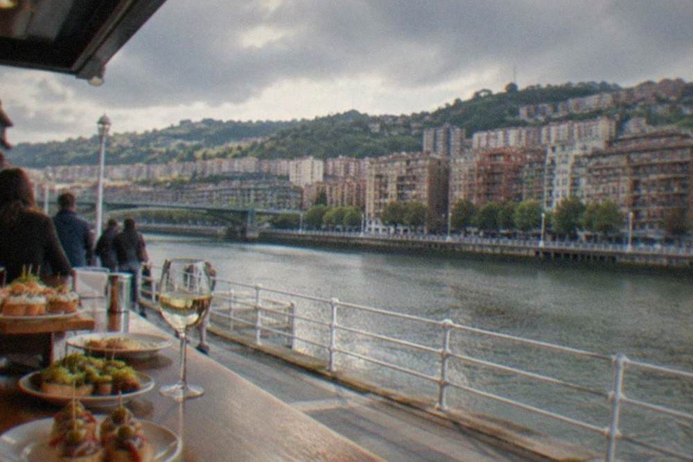 A busy pintxos bar counter with plates and glass of txakoli in Bilbao