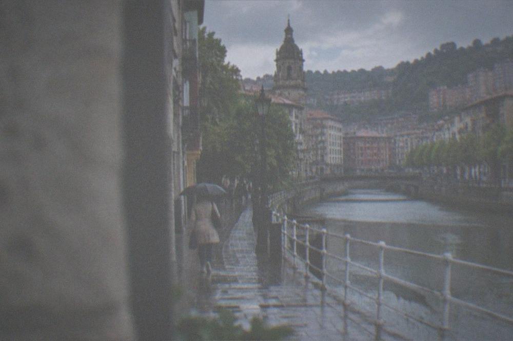 A quiet Bilbao street on a Sunday morning with a church bell tower above the rooftops