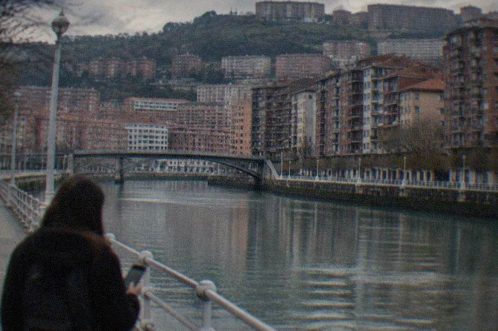 A phone displaying a map of Bilbao streets held above a cafe table
