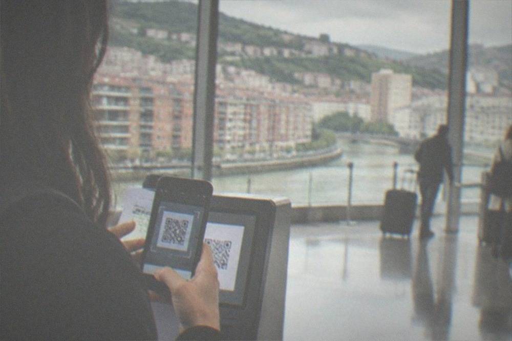A traveler scanning a QR code on a phone at an airport arrivals hall
