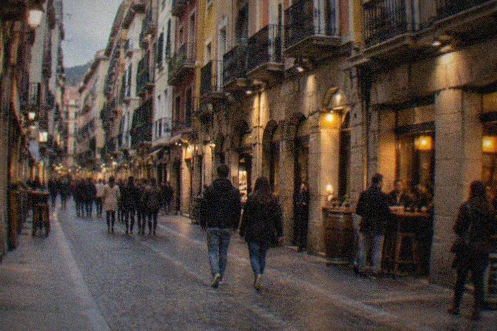 An evening street scene in Bilbao's Casco Viejo with lit bar fronts and people walking