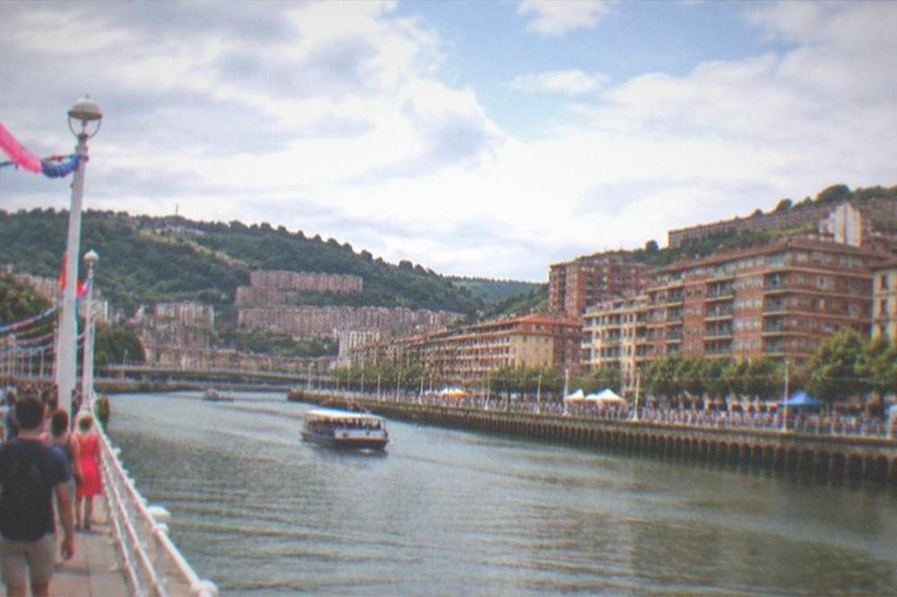 Crowds and festival decorations along the river in Bilbao during Aste Nagusia in August