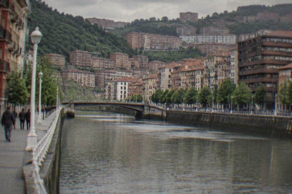 Painted shutters and small graffiti pieces on a narrow street in an old Bilbao district