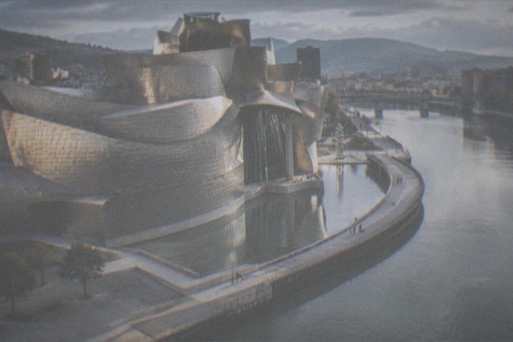 The Guggenheim Museum Bilbao's curved titanium facade seen across the river in daylight