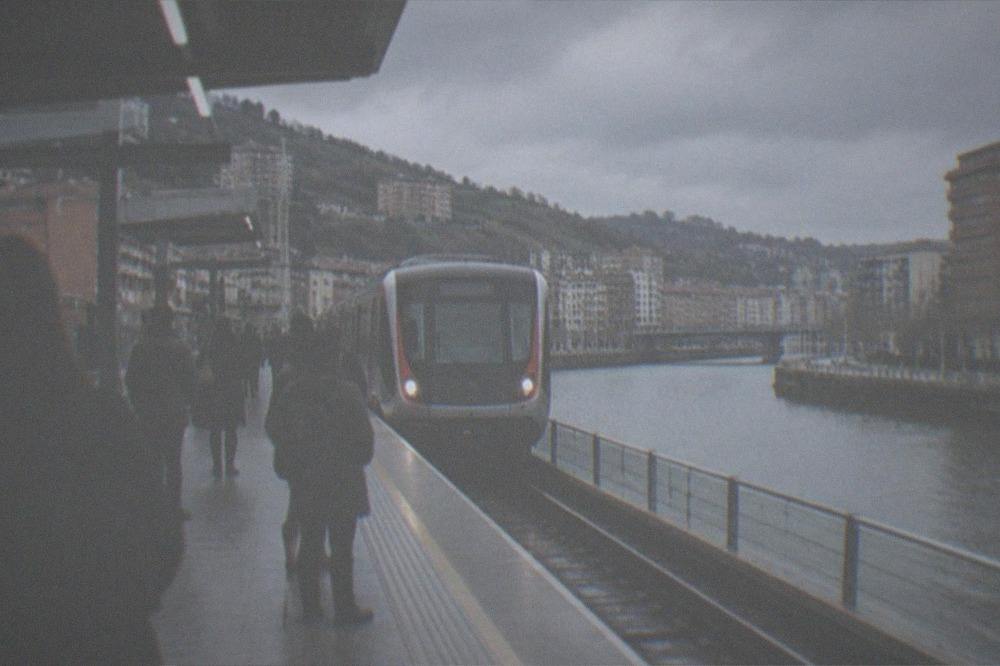 A train arriving at a metro station platform in Bilbao with passengers waiting