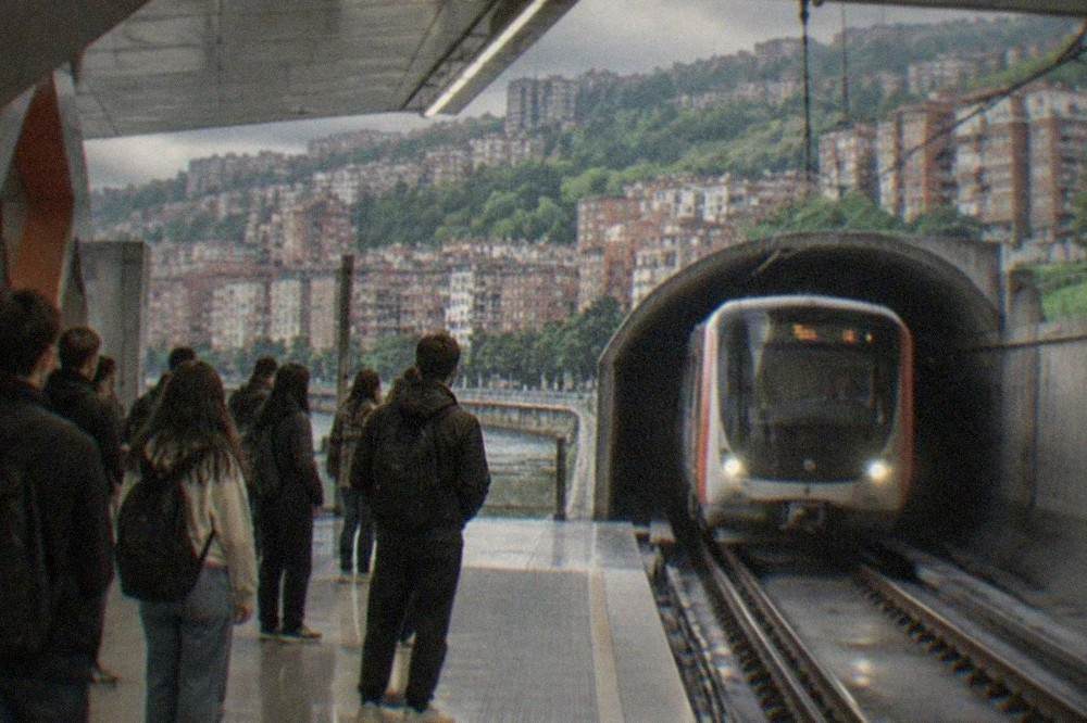 A metro train arriving at an underground Bilbao station with students waiting on the platform