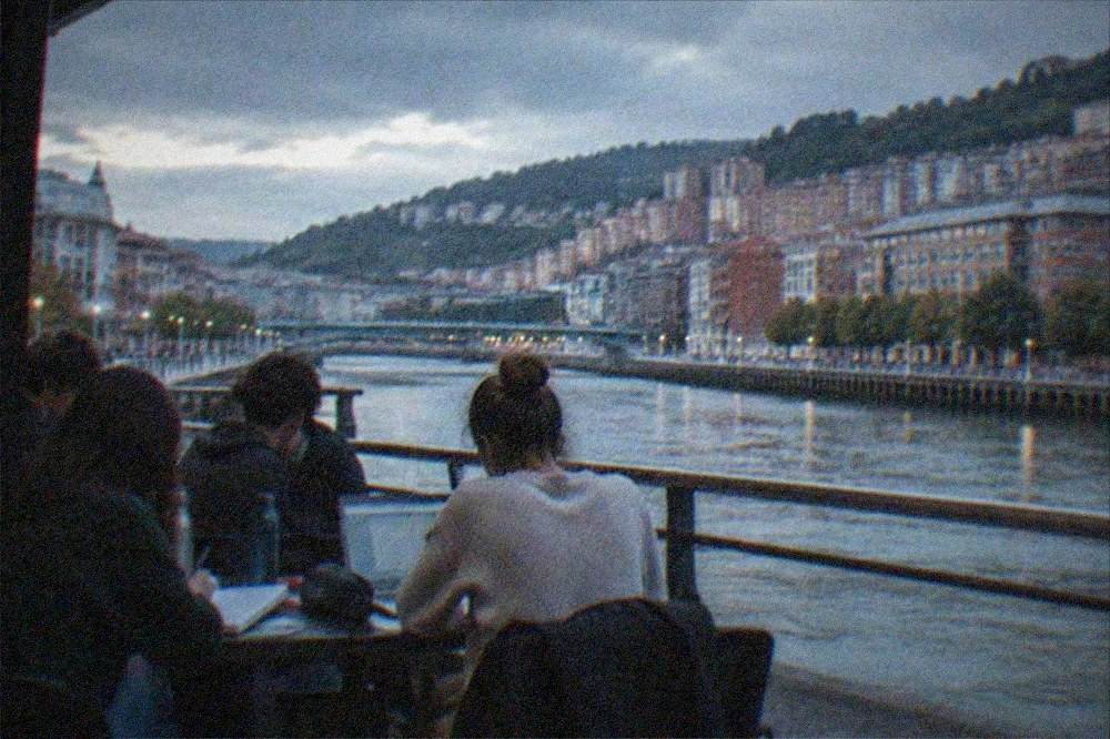 Students studying together at a riverside terrace table in central Bilbao