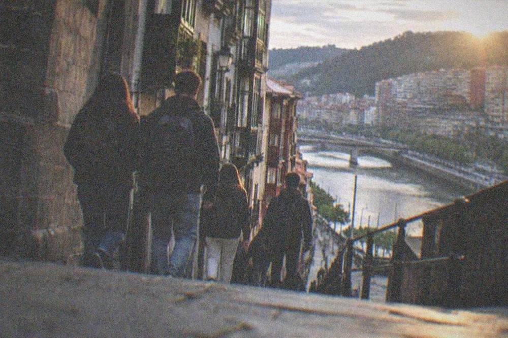 Group of students with backpacks walking down a Bilbao old town street in the evening