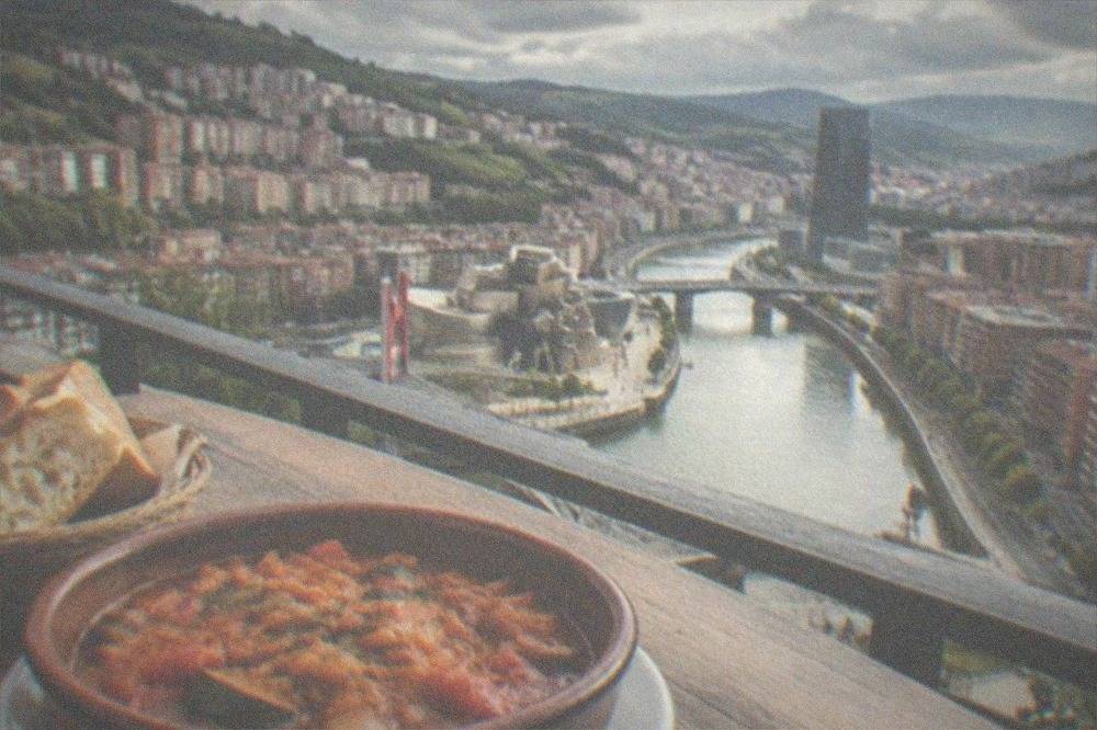 A rustic plate of pisto, Basque vegetable stew, with bread on a wooden table