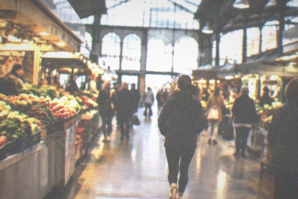 Interior of a Bilbao covered market with produce stalls and shoppers under a high ceiling