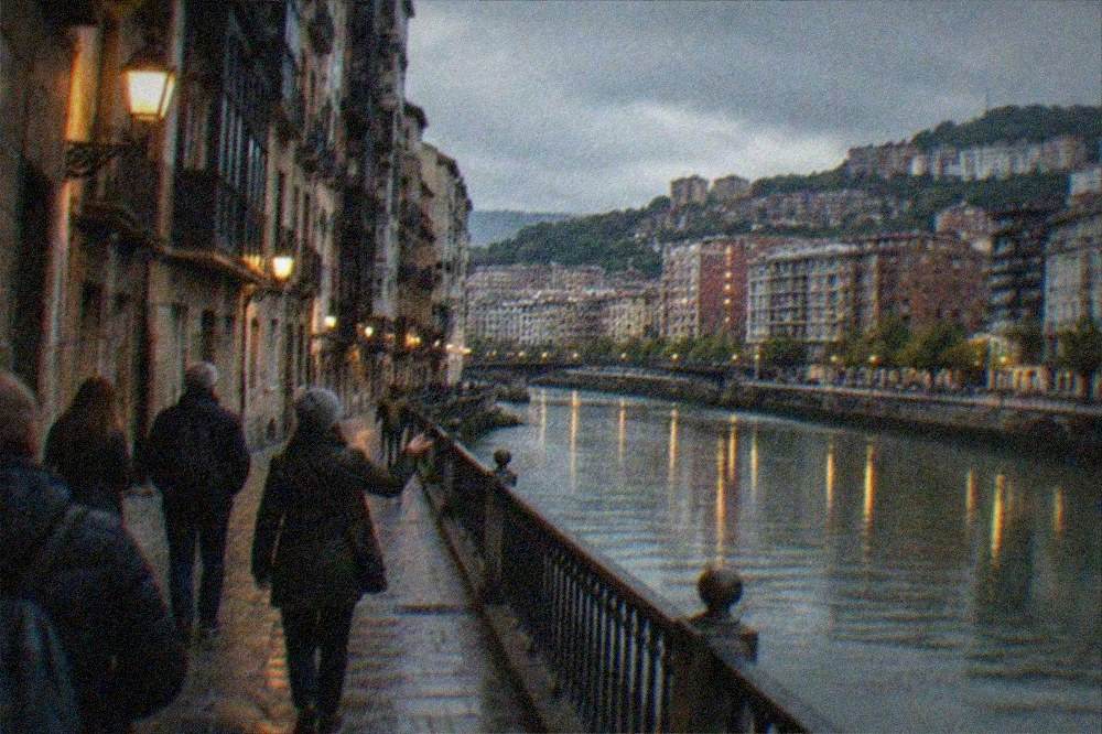 A small group following a guide along a lantern-lit street in Bilbao's old town in the evening