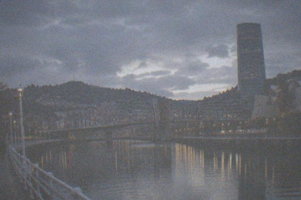 The estuary waterfront in Bilbao at dusk with bridges and towers lit