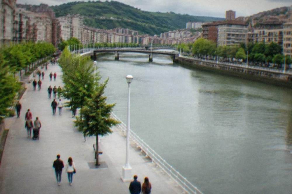Families and couples strolling a wide promenade beside the river in Bilbao