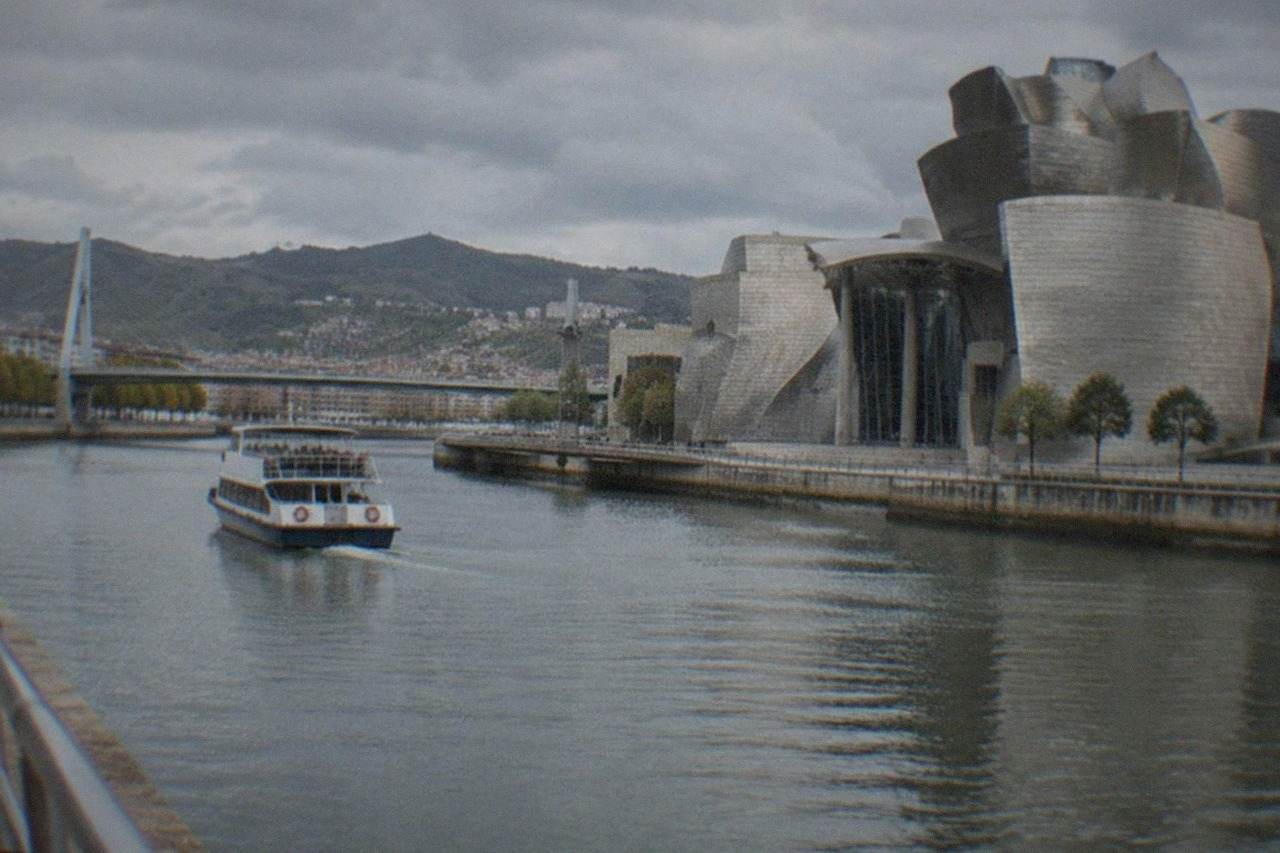 The Guggenheim Museum Bilbao beside the Nervion estuary under a partly cloudy sky