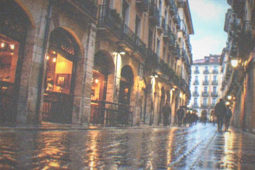 Wet cobblestone street in Bilbao's Casco Viejo reflecting shop lights after rain