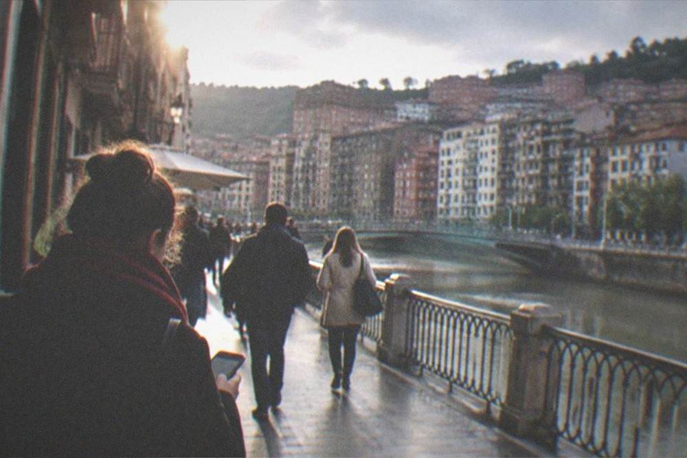 A person holding a phone securely while walking through a busy pedestrian street in Bilbao's Old Town
