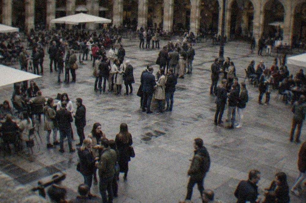 An evening crowd standing with wine glasses around the arcaded Plaza Nueva in Bilbao's old town