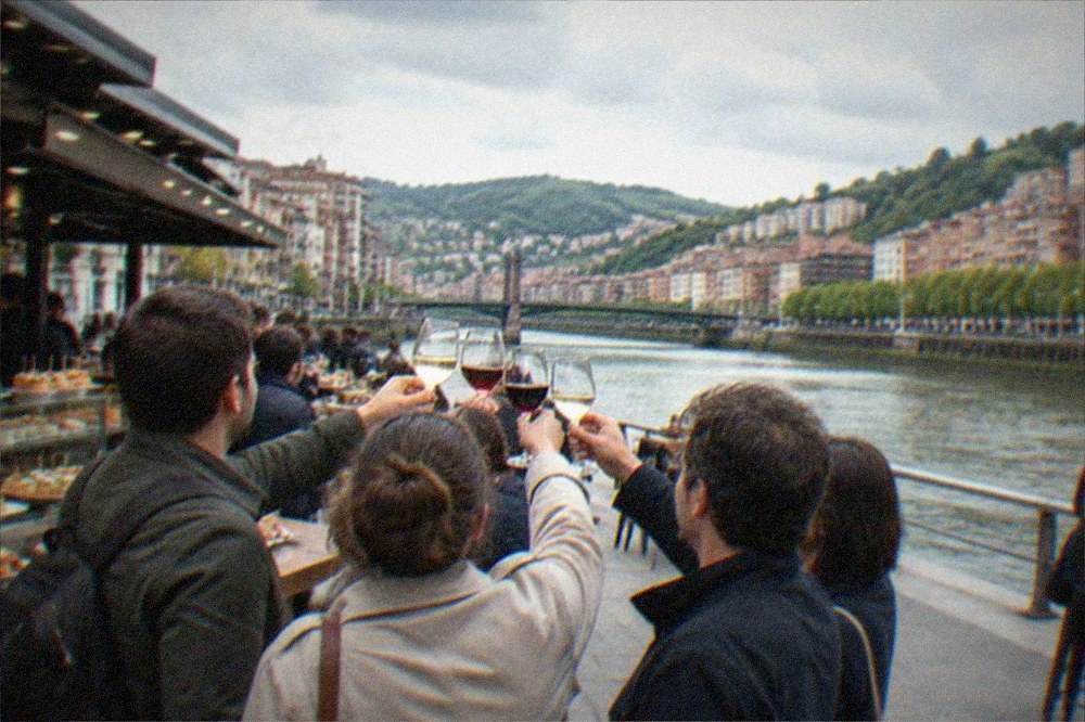 A small group with a guide raising wine glasses at a busy Bilbao pintxos counter