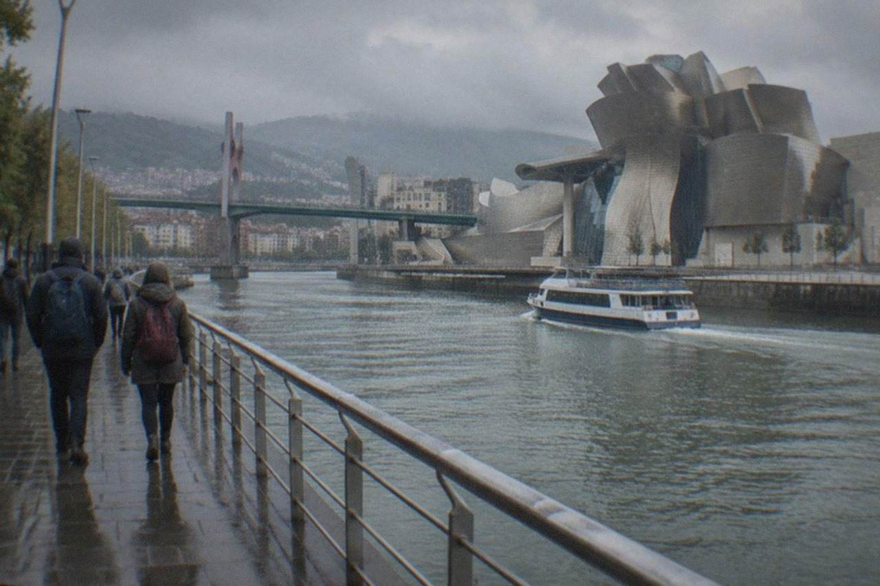 Backpackers walking along the Nervion riverfront in Bilbao with the Guggenheim Museum in the background