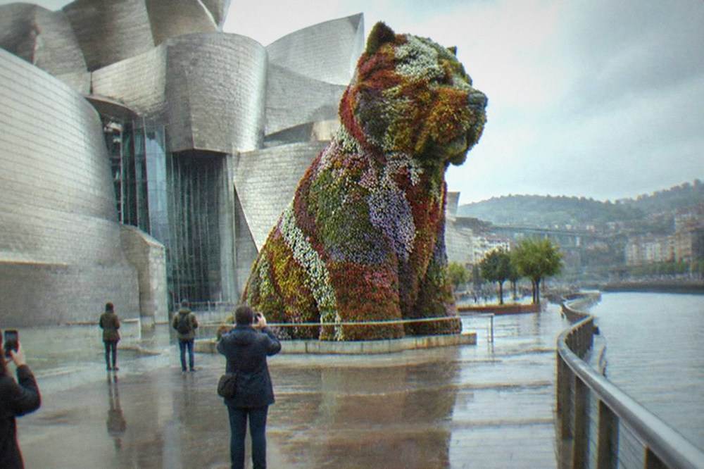 Visitors photographing the flower-covered Puppy sculpture outside the Guggenheim Museum in Bilbao