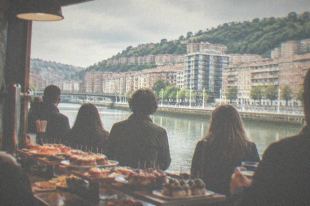 Crowd standing at a busy pintxo bar counter in Bilbao with tapas displayed on the bar top