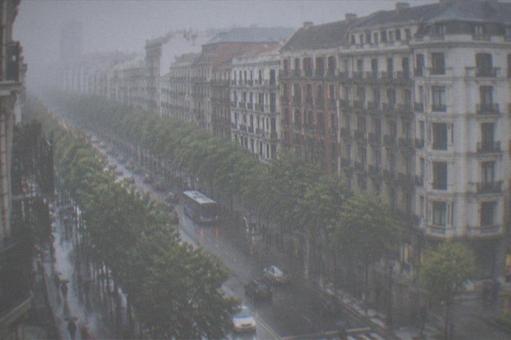 Rainy street scene in the Ensanche district of Bilbao with umbrellas and wet pavement