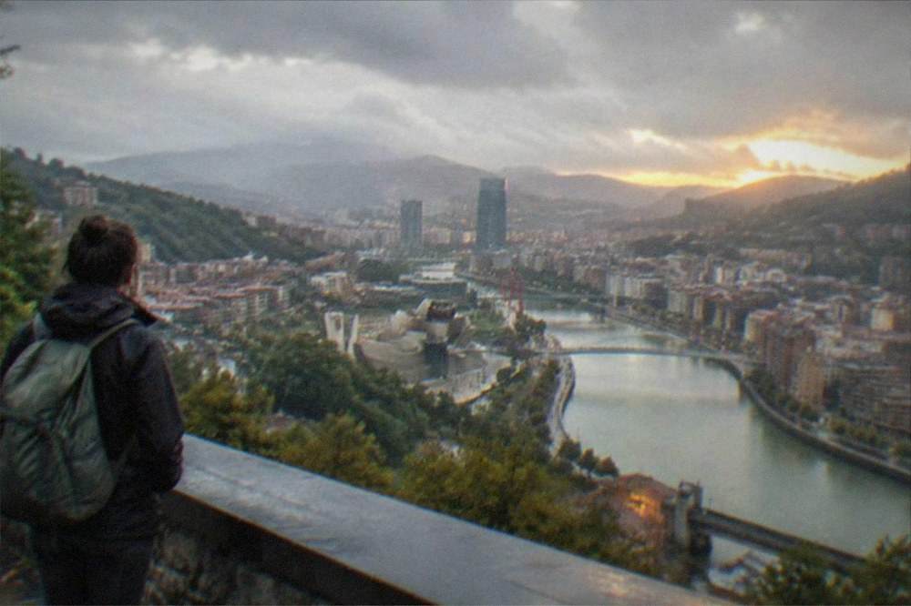 Traveller with a backpack looking out over Bilbao from the Artxanda hilltop viewpoint at sunset
