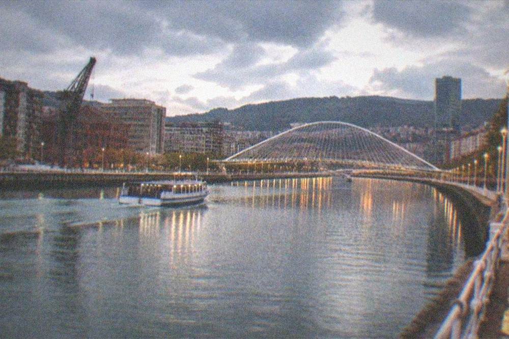 Evening view over the Nervion estuary in Bilbao with the Zubizuri bridge and city lights reflecting in the water