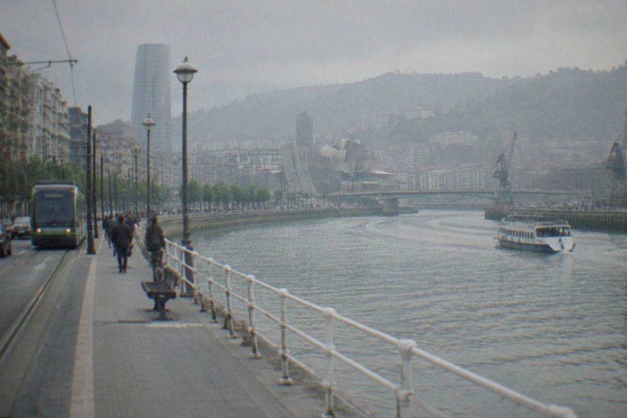 Cars and trams sharing a street in central Bilbao with the Nervion river alongside