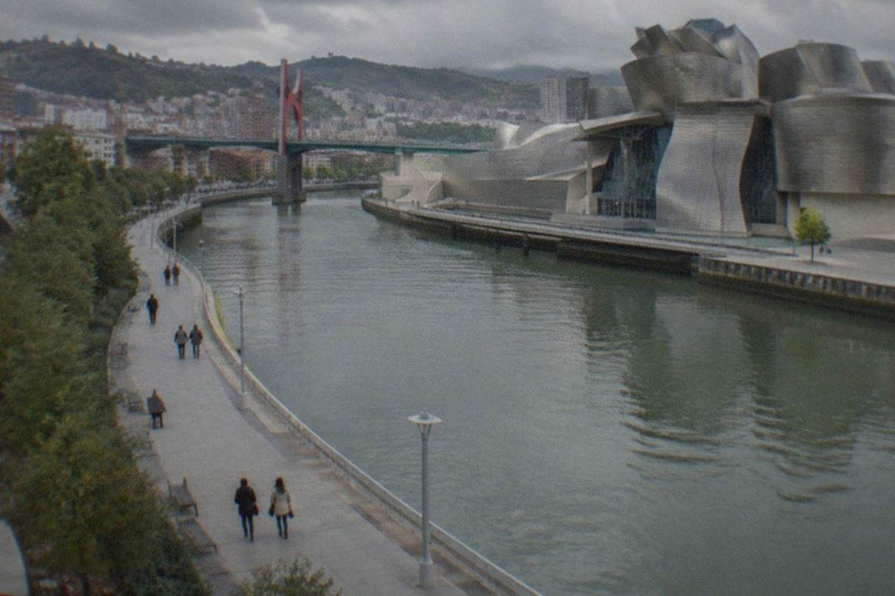A wide accessible riverside promenade in Bilbao with the Guggenheim Museum's curved titanium facade in the background