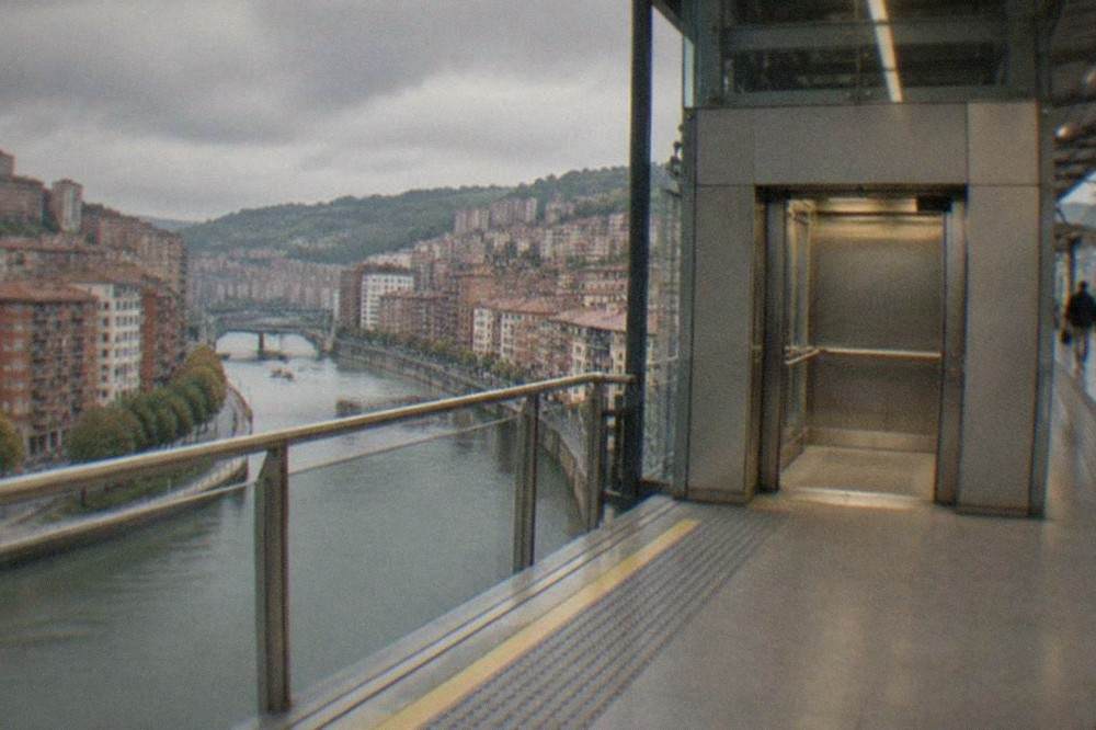 A Metro Bilbao station platform with a wide elevator door opening next to tactile paving and bright signage