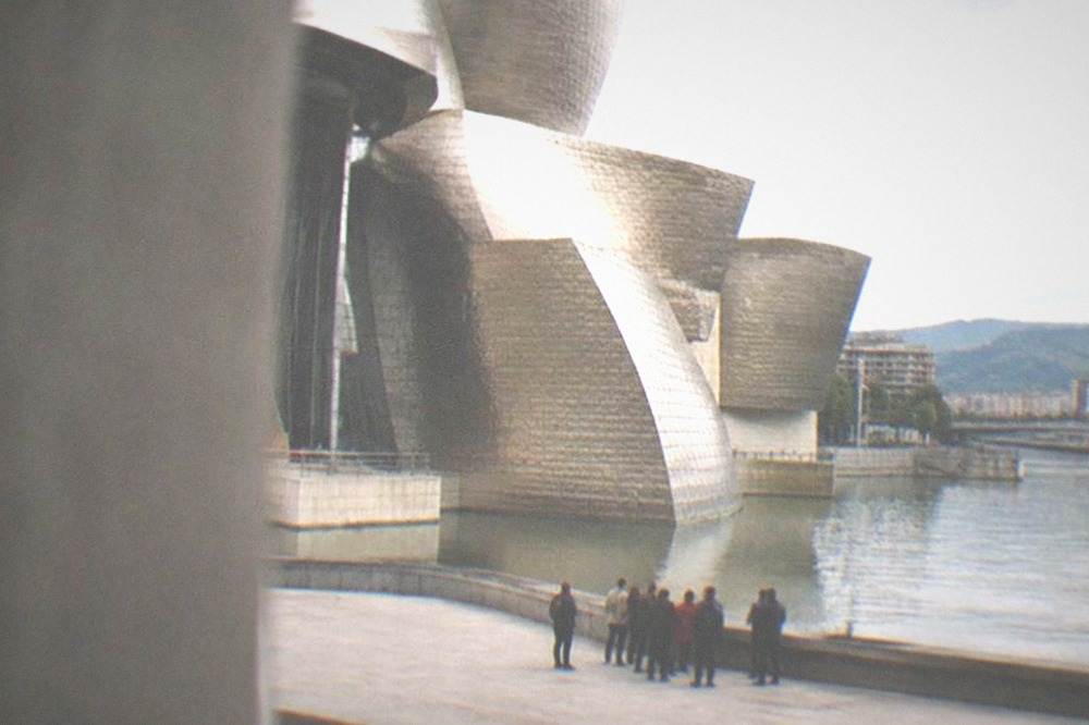 A small tour group gathered on the flat riverside walkway in front of the Guggenheim Museum in Bilbao