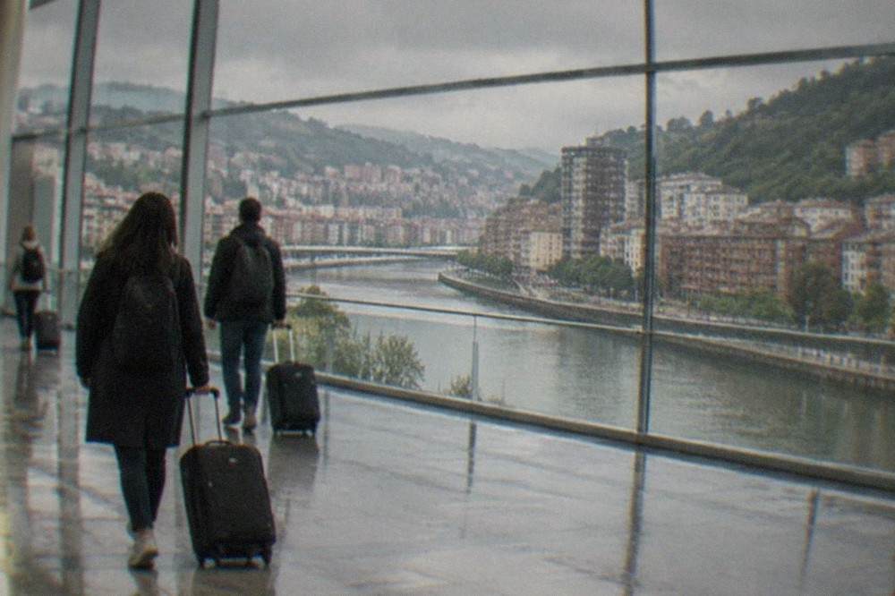Travelers with rolling suitcases walking through a bright modern airport terminal concourse