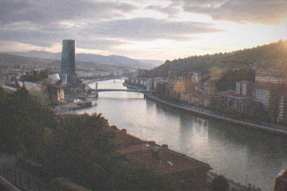 A city skyline of a northern Spanish city at dusk seen across a river