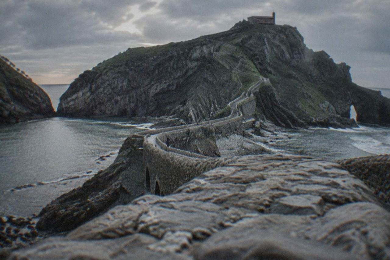 A stone hermitage on a rocky islet connected to the Basque coast by a narrow causeway with a long flight of steps
