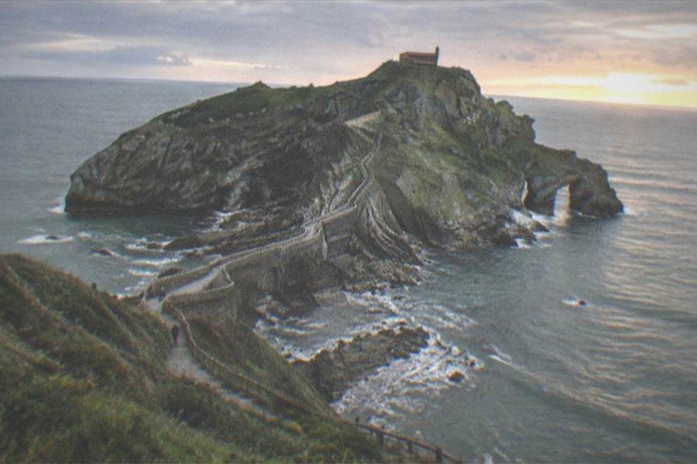 The small hermitage of San Juan de Gaztelugatxe silhouetted on the summit of a rocky islet at sunset