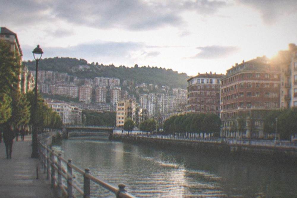 A street in central Bilbao with bilingual Basque and Spanish signage and the Basque flag on a building