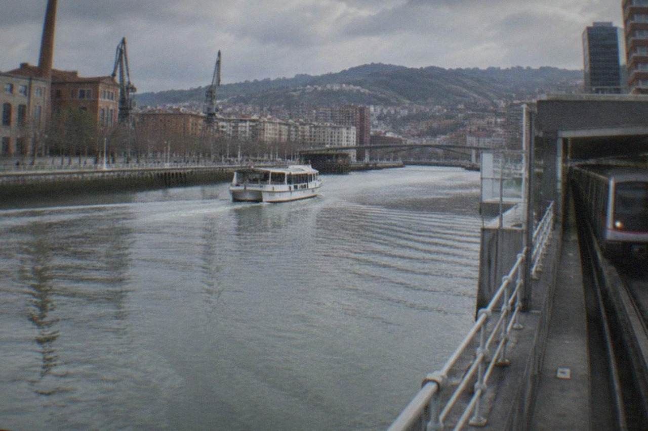 A Bilbao metro train arriving at an underground station platform beside the Nervion estuary