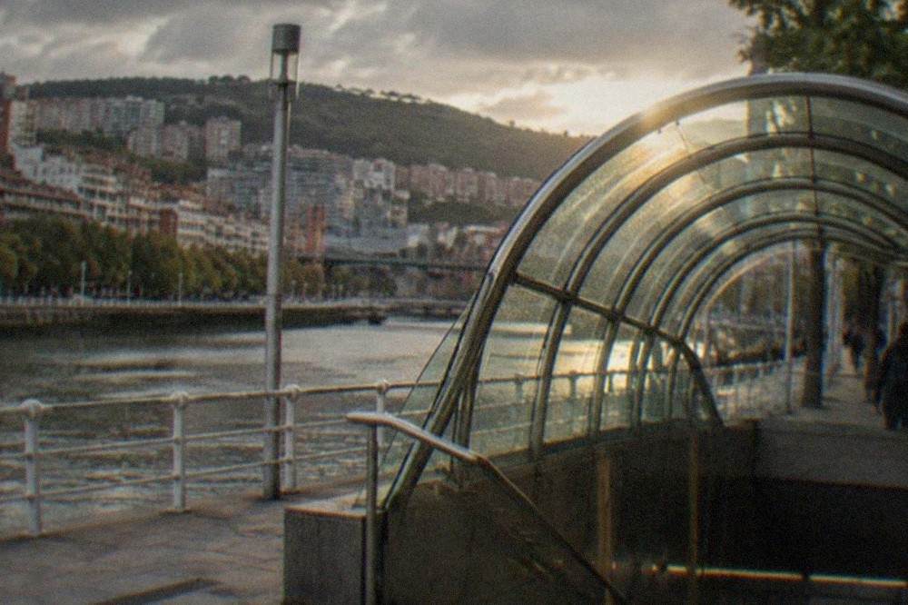The curved glass canopy of a Bilbao metro entrance on a city street