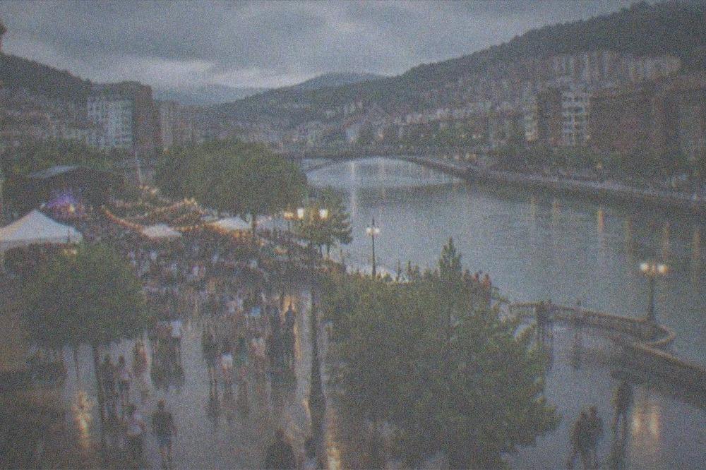 Crowds crossing a festive plaza in Bilbao at dusk during a summer festival