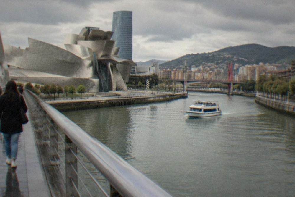 Visitors walking across a bridge over the Nervion river toward the Bilbao city centre