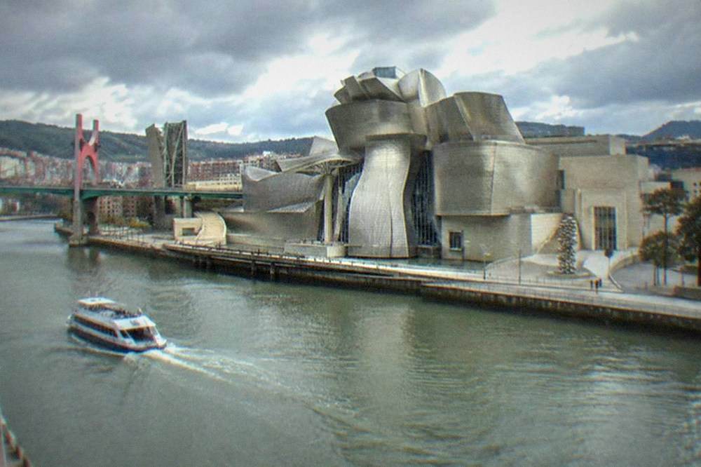 The titanium curves of the Guggenheim Museum Bilbao beside the Nervion river on a cloudy day