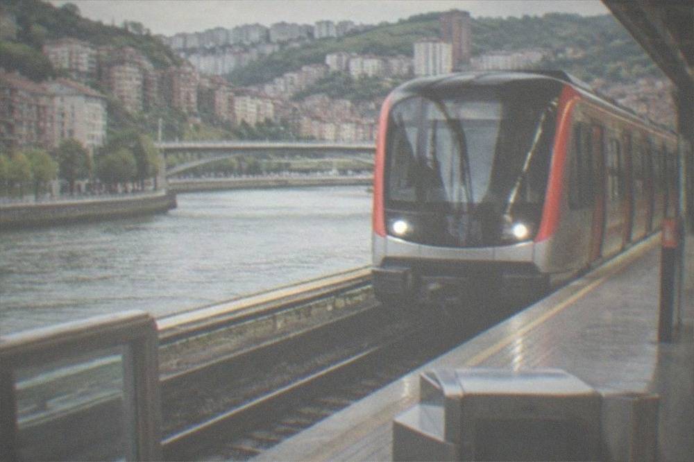A Metro Bilbao train arriving at a station platform with a Barik card reader at the gate