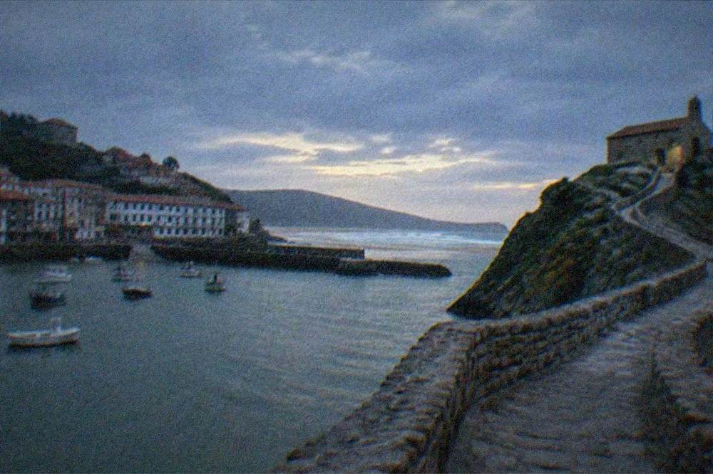 A stone hermitage on a rocky islet connected by a narrow winding causeway above the sea
