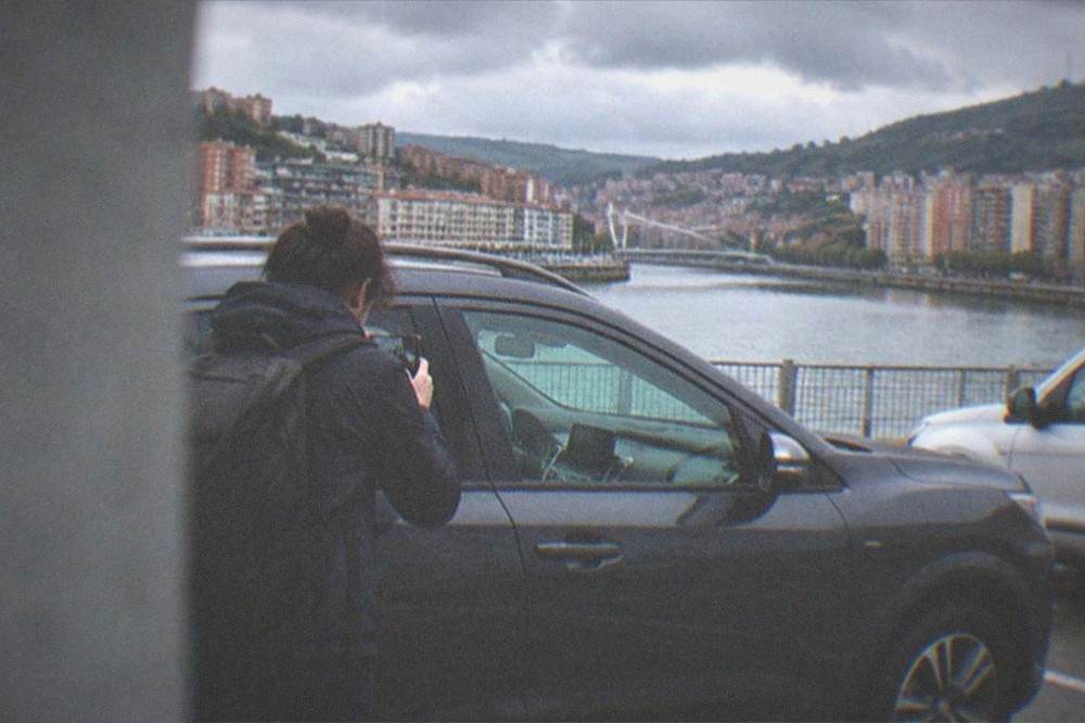 A traveller photographing the panels of a rental car in an airport parking bay