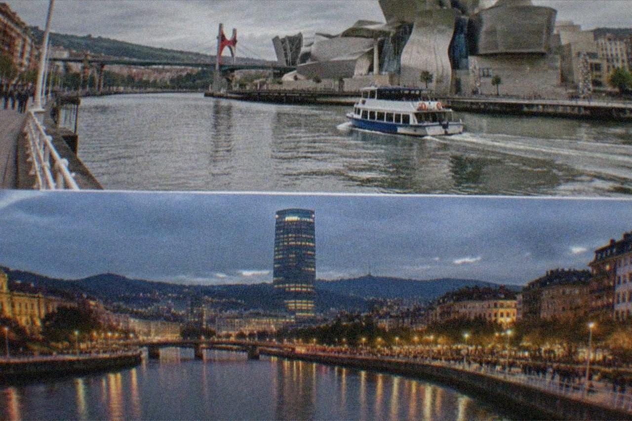 Evening view over Bilbao's illuminated city centre with the Nervion river and crowded riverside walkways