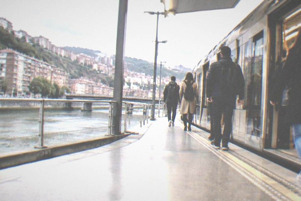 Commuters boarding a modern Bilbao metro train on a bright station platform
